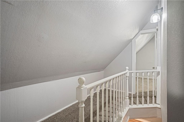 stairs featuring carpet flooring, a textured ceiling, and vaulted ceiling