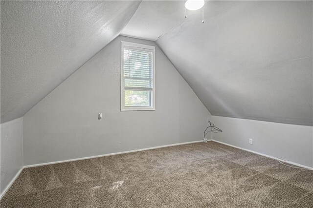 bonus room with carpet, vaulted ceiling, and a textured ceiling