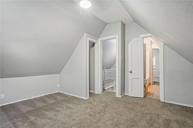 bonus room featuring carpet floors, a textured ceiling, lofted ceiling, and ceiling fan