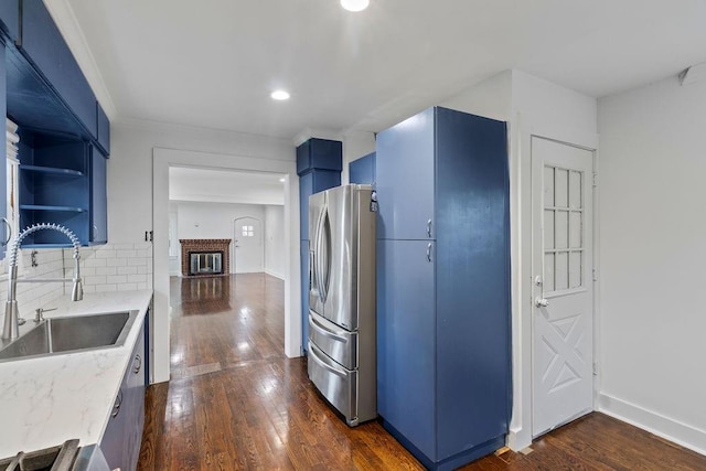 kitchen with blue cabinetry, sink, dark wood-type flooring, and stainless steel refrigerator