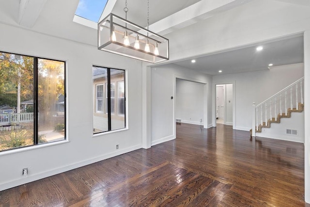 spare room with beamed ceiling, dark wood-type flooring, and a skylight