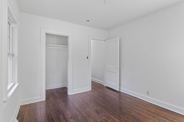 unfurnished bedroom with crown molding, a closet, and dark hardwood / wood-style flooring