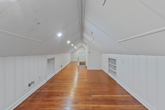 additional living space featuring wood walls, wood-type flooring, built in features, and vaulted ceiling