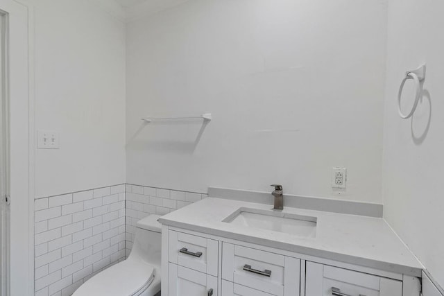 bathroom with vanity, toilet, and tile walls