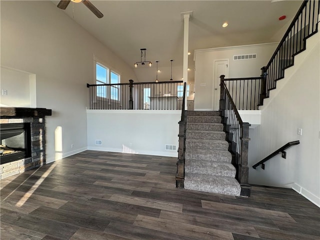 stairs featuring a fireplace, ceiling fan, hardwood / wood-style floors, and a high ceiling