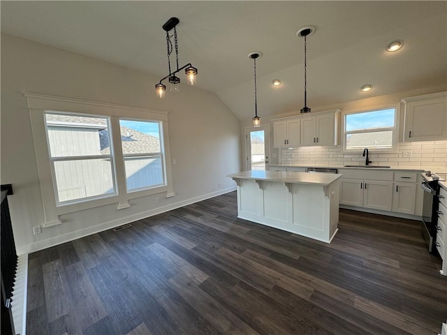 kitchen featuring white cabinetry, backsplash, pendant lighting, vaulted ceiling, and a kitchen island