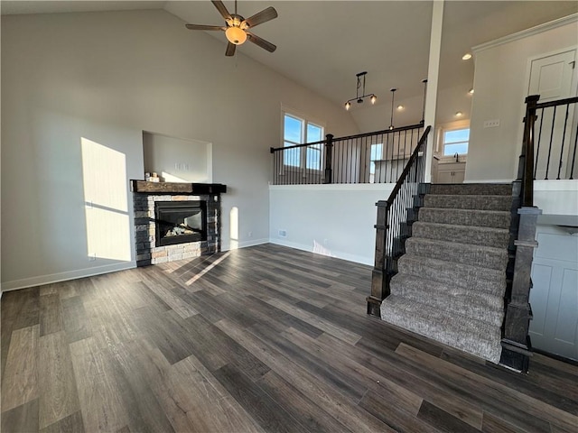 unfurnished living room featuring high vaulted ceiling, ceiling fan, stairway, healthy amount of natural light, and wood finished floors