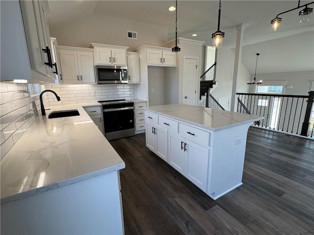 kitchen featuring a sink, electric range oven, stainless steel microwave, backsplash, and dark wood finished floors