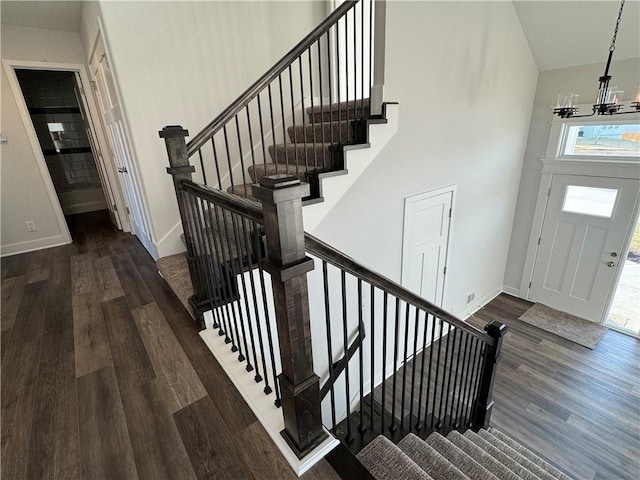 stairway with wood finished floors, a chandelier, healthy amount of natural light, and baseboards