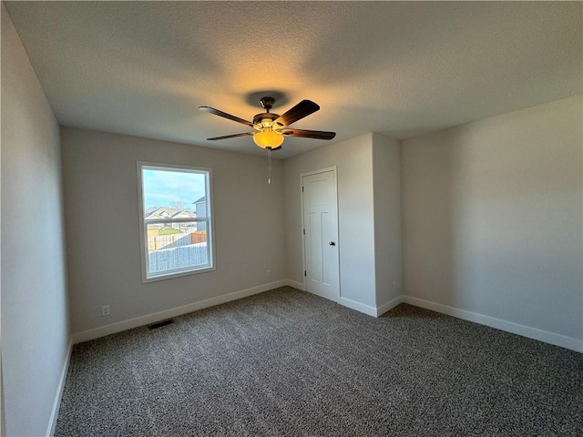unfurnished bedroom featuring carpet floors, a textured ceiling, baseboards, and ceiling fan