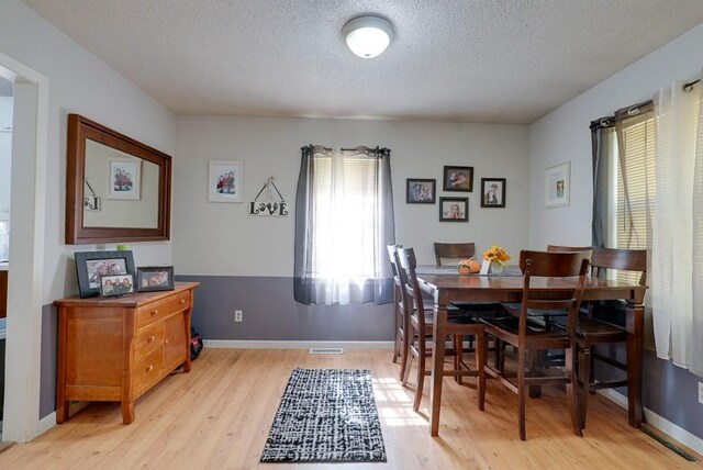 dining area featuring a textured ceiling and light wood-type flooring