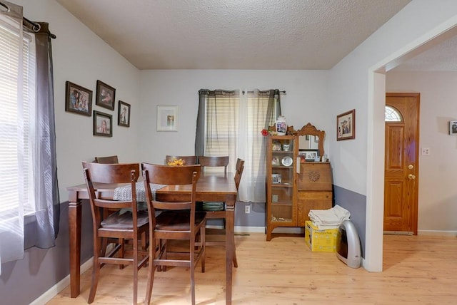 dining room featuring light wood-type flooring and a textured ceiling