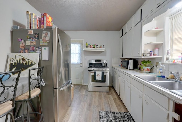 kitchen featuring a wealth of natural light, appliances with stainless steel finishes, light hardwood / wood-style floors, and white cabinetry