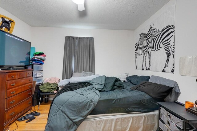 bedroom featuring wood-type flooring, ceiling fan, and a textured ceiling