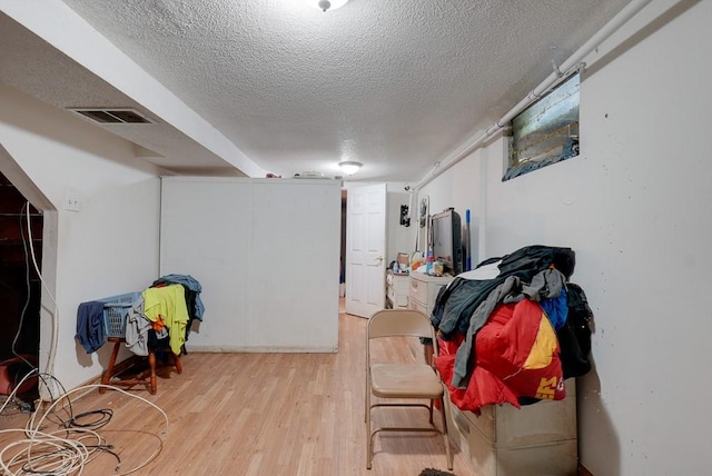 basement with light wood-type flooring and a textured ceiling