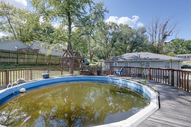 view of swimming pool with a wooden deck and a playground