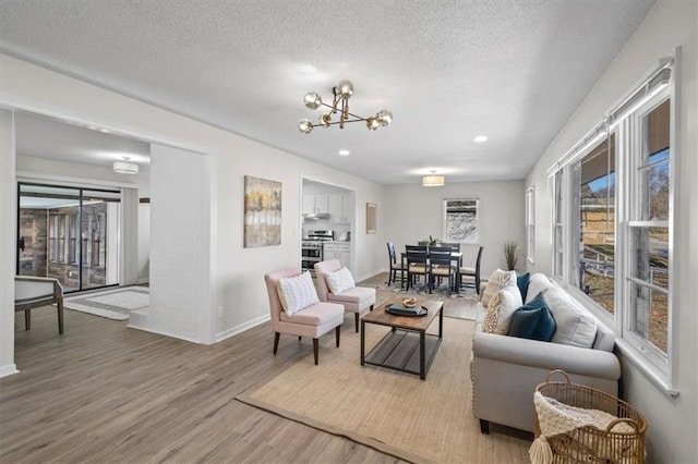 living room featuring light hardwood / wood-style flooring, a textured ceiling, and an inviting chandelier