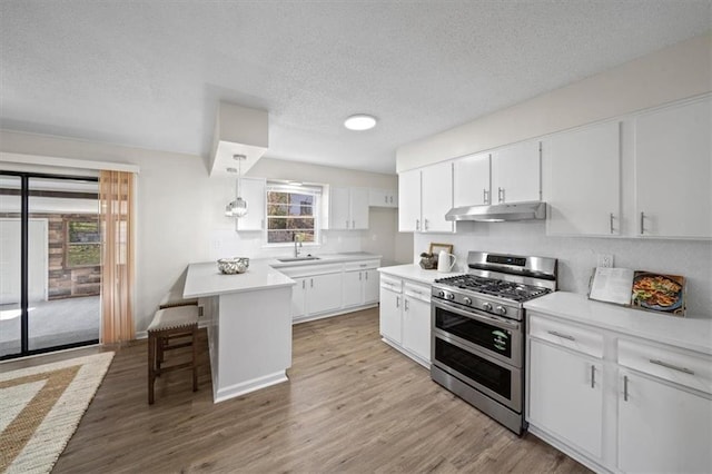 kitchen with a breakfast bar, range with two ovens, light hardwood / wood-style flooring, white cabinetry, and hanging light fixtures