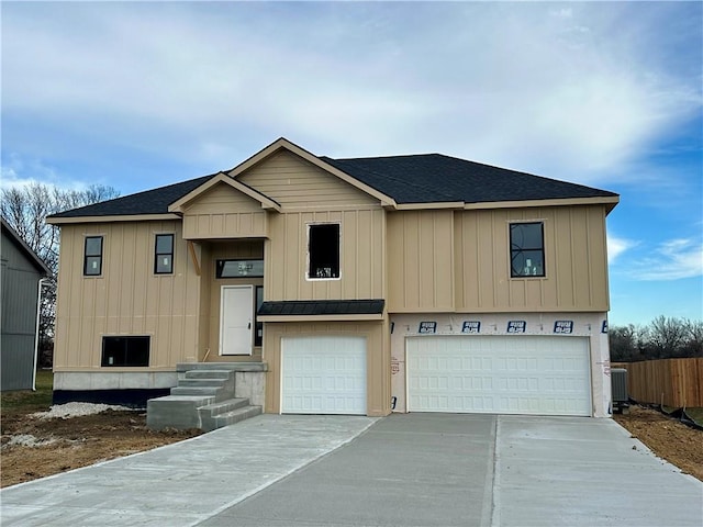 view of front of house with roof with shingles, central air condition unit, concrete driveway, fence, and a garage