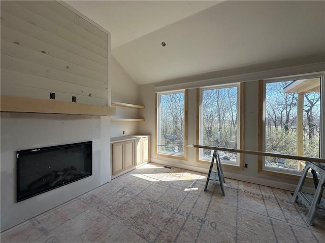 unfurnished living room with a glass covered fireplace and vaulted ceiling