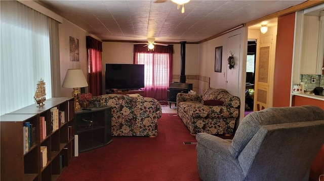 carpeted living room featuring a wood stove and ceiling fan