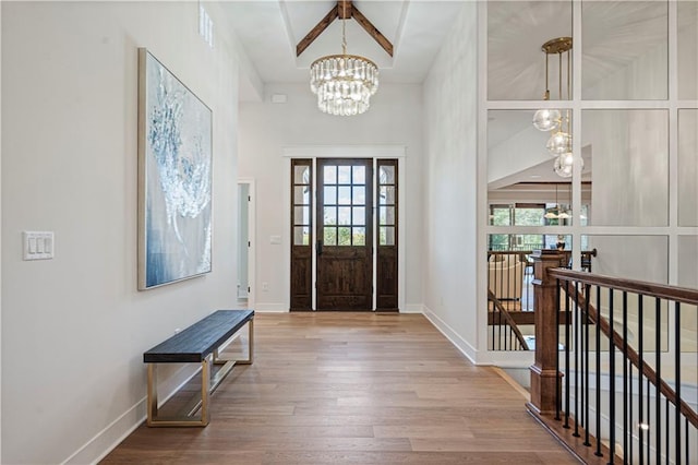 entryway featuring a healthy amount of sunlight, a high ceiling, an inviting chandelier, and wood-type flooring