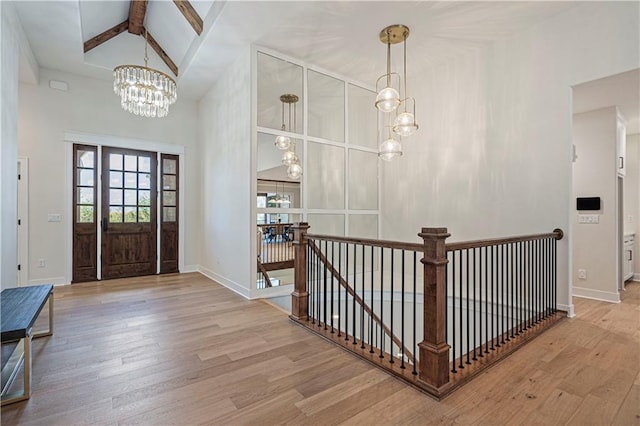 entrance foyer with wood-type flooring, beamed ceiling, a chandelier, and high vaulted ceiling