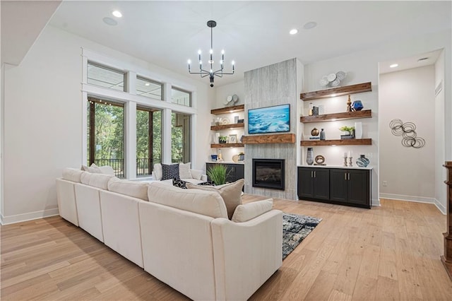 living room with light wood-type flooring, a large fireplace, and a chandelier