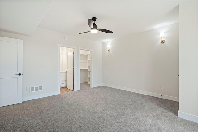 unfurnished bedroom with a spacious closet, light carpet, a closet, and ceiling fan