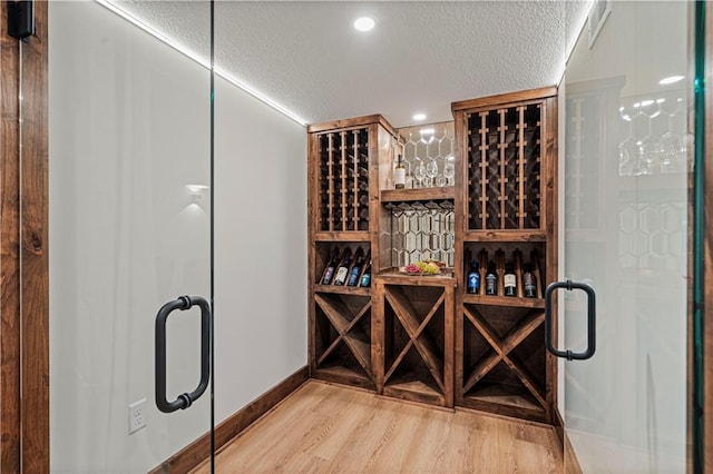 wine area with light hardwood / wood-style flooring and a textured ceiling