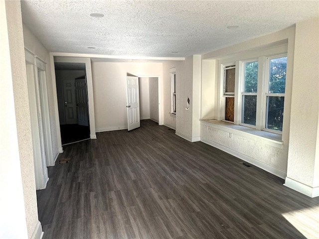 empty room with a textured ceiling and dark hardwood / wood-style floors