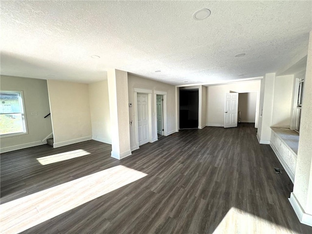 unfurnished living room with a textured ceiling and dark wood-type flooring