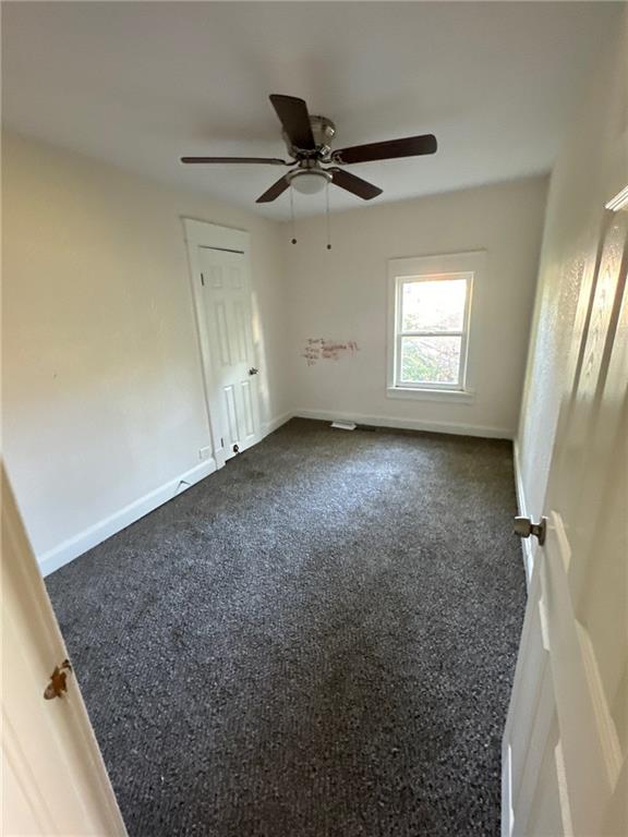 unfurnished bedroom featuring ceiling fan and dark colored carpet