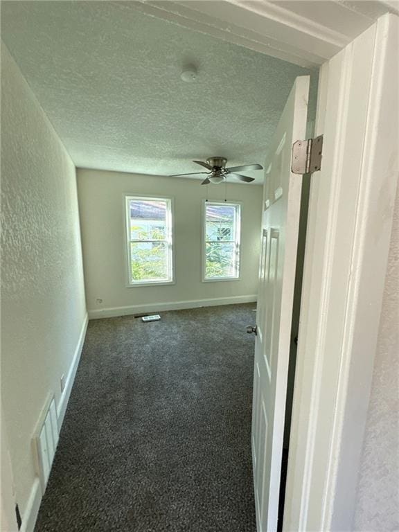 carpeted spare room featuring ceiling fan and a textured ceiling