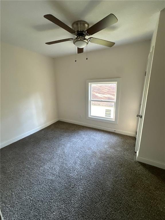 unfurnished room featuring ceiling fan and dark carpet