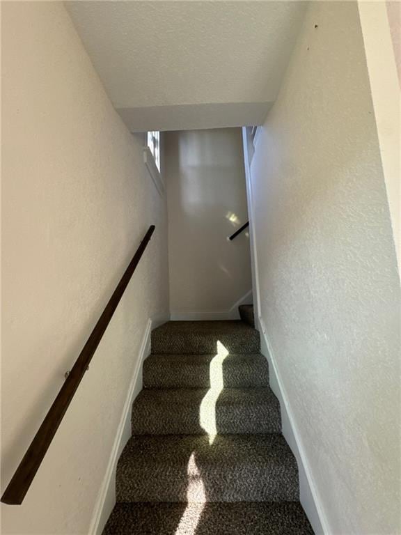 stairs with carpet and a textured ceiling