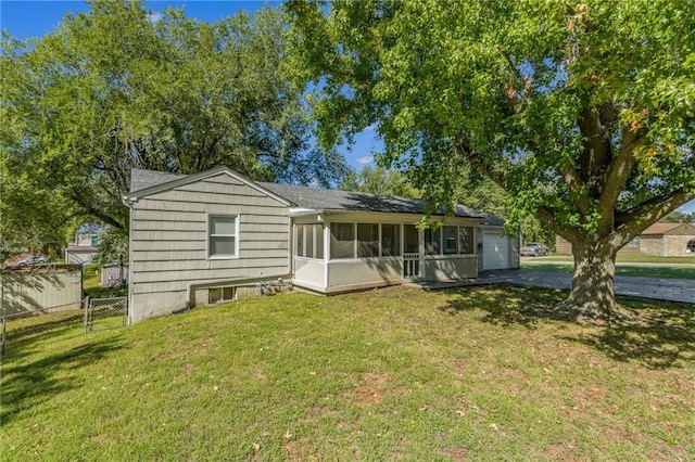 rear view of house featuring a sunroom and a yard