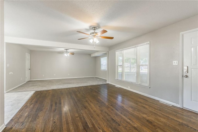 unfurnished living room with ceiling fan, a textured ceiling, and dark hardwood / wood-style flooring