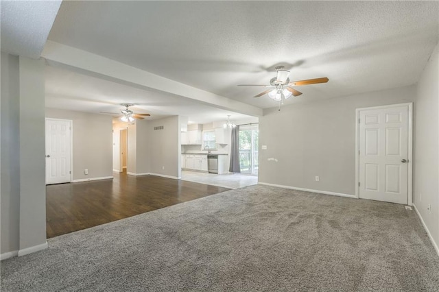 unfurnished living room with a textured ceiling, ceiling fan with notable chandelier, sink, and hardwood / wood-style floors