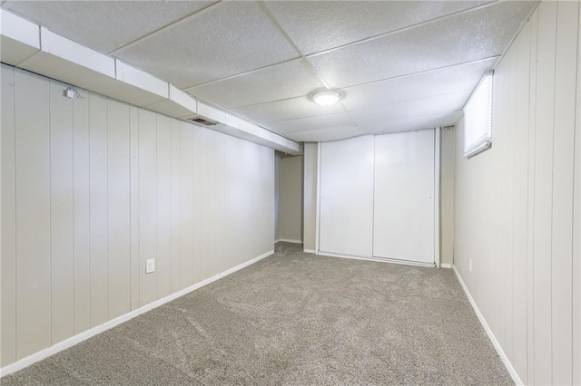 basement with light colored carpet and wooden walls