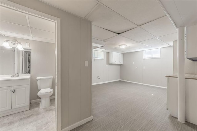 basement featuring a drop ceiling and wooden walls