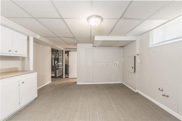 basement with light hardwood / wood-style flooring and a paneled ceiling