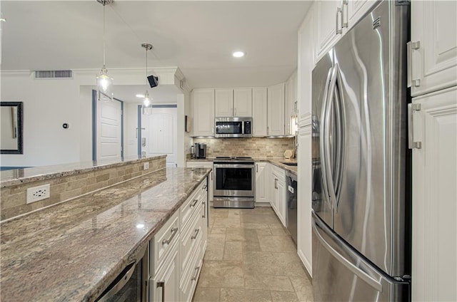 kitchen featuring white cabinets, decorative light fixtures, stainless steel appliances, and dark stone counters