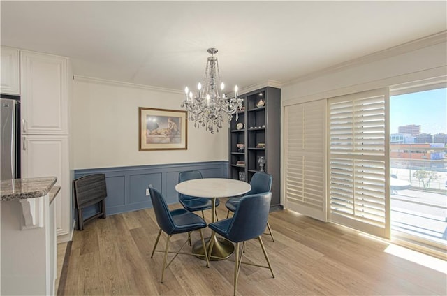 dining area featuring light hardwood / wood-style floors, an inviting chandelier, and crown molding