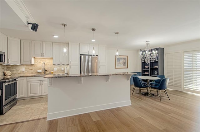 kitchen with white cabinets, a center island, light hardwood / wood-style floors, and stainless steel appliances