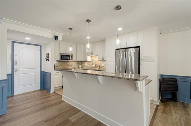 kitchen with white cabinets, sink, appliances with stainless steel finishes, and light hardwood / wood-style flooring