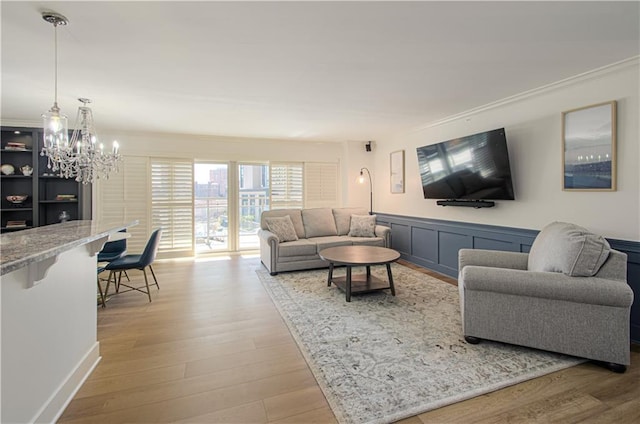 living room with light hardwood / wood-style floors and a notable chandelier