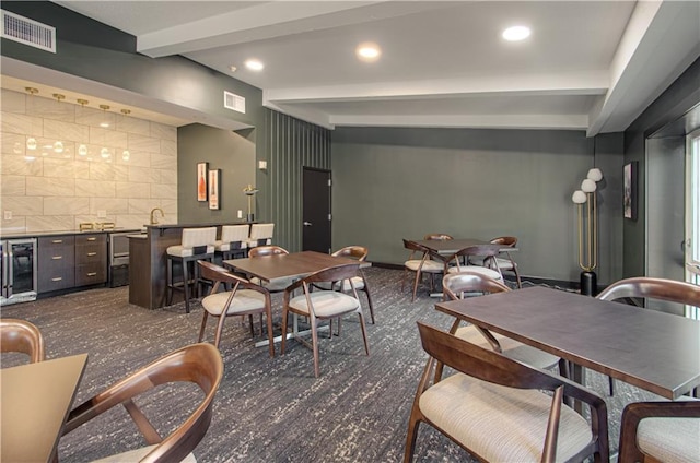 dining area featuring beam ceiling, wine cooler, and bar