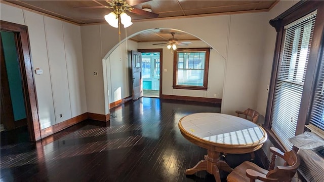 dining area with ceiling fan, ornamental molding, and dark wood-type flooring