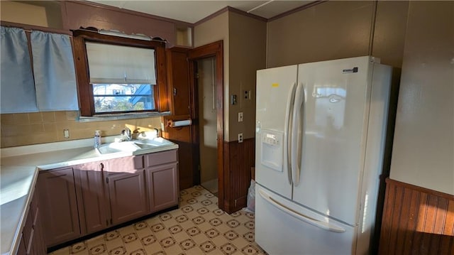 kitchen featuring decorative backsplash, sink, and white refrigerator with ice dispenser